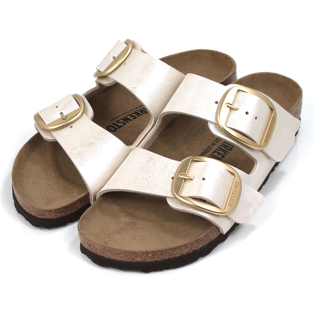 Birkenstock off white metallic two strap open back sandals. Large gold buckles. Cork inner soles and black rubber soles. Angled view.