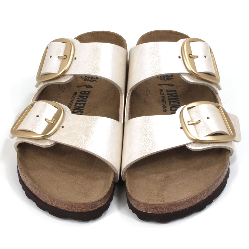 Birkenstock off white metallic two strap open back sandals. Large gold buckles. Cork inner soles and black rubber soles. Front view.