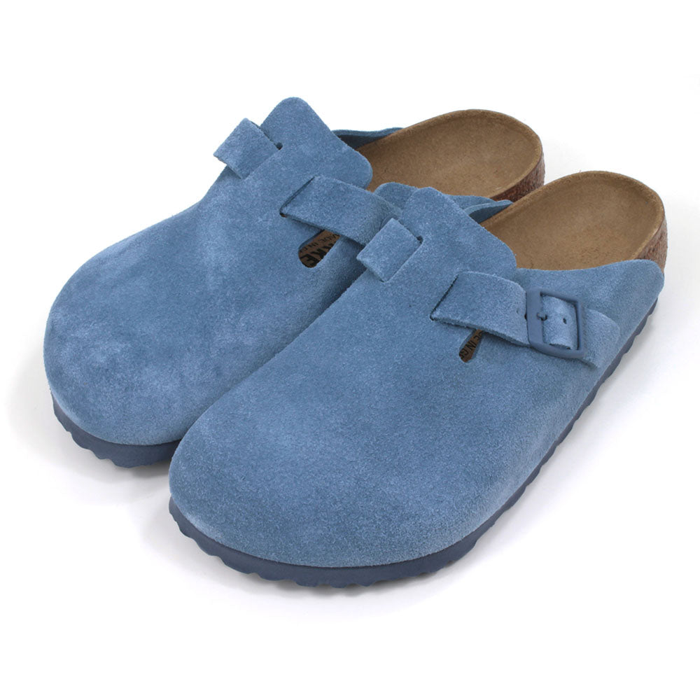 Birkenstock sky blue suede clogs with buckled strap. Open backs and sculpted inner soles. Cork and rubber soles. Angled view.