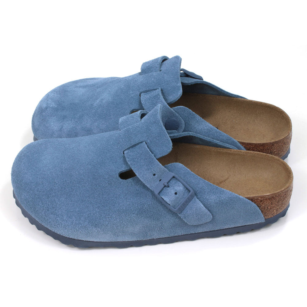 Birkenstock sky blue suede clogs with buckled strap. Open backs and sculpted inner soles. Cork and rubber soles. Side view.