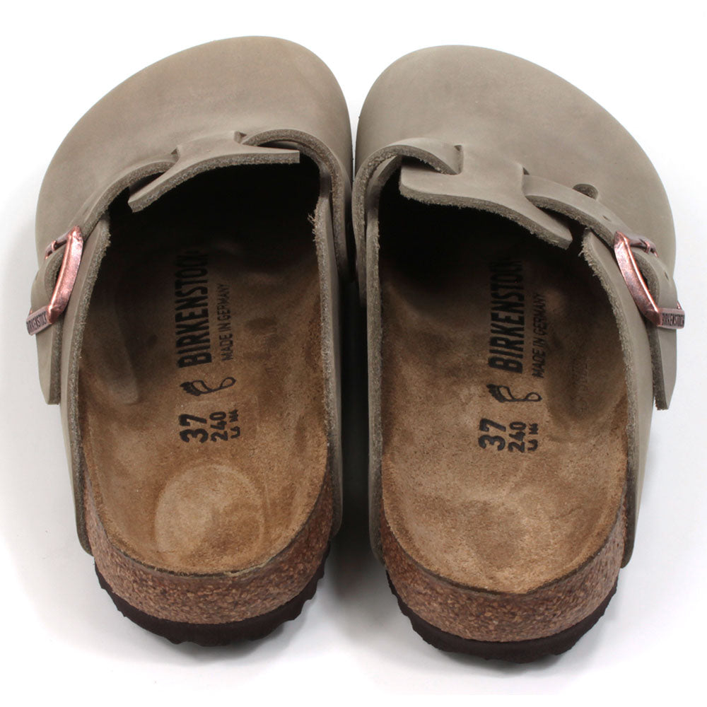 Birkenstock enclosed feet, open back clogs. Brown sculpted inner sole. Black rubber soles. Mid brown with copper coloured buckle on cross foot adjustment strap. Back view.