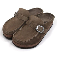 Birkenstock Buckley mid taupe mule shoes with over the foot strap with silver buckle. Moccasin styling. Cork and black rubber soles. Angled veiw.