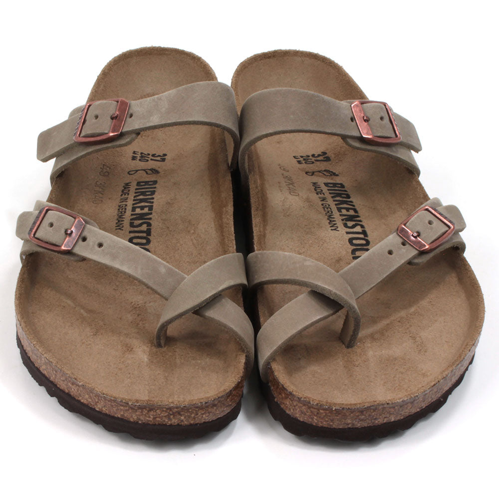 Birkenstock Mayari strapped sandals with open back design. Sculpted inner sole. Sole made of cork and black rubber. Straps over the big toe form a toe post design with another strap across the foot near the ankle. Adjustment with copper coloured buckles. Straps are a mid brown colour. Front view.
