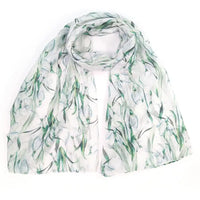 A lightweight white scarf with a watercolor-style green botanical print, draped and folded on a plain white background.