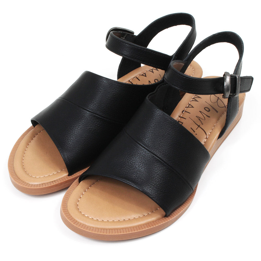 Blowfish Malibu black sandals with buckled over the ankle straps. Light brown soles. Angled view.