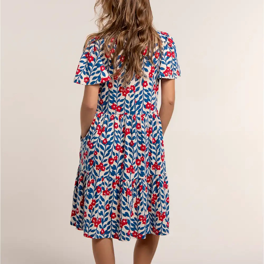 Woman wearing a floral dress with red flowers on a beige background
