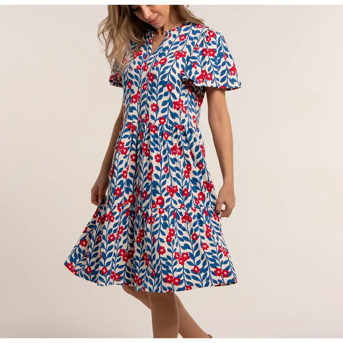 Woman wearing a floral dress with red flowers on a beige background
