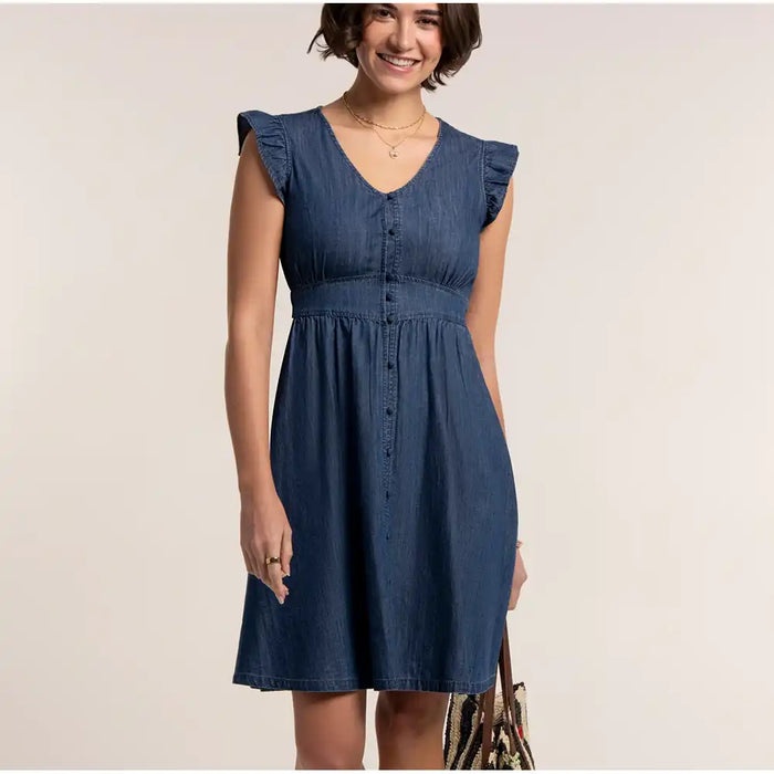 Woman wearing a blue denim dress against a plain background