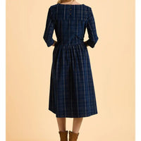 Blue plaid dress worn by a person on a beige background