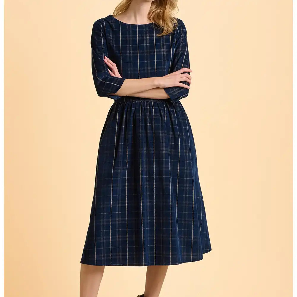 Woman wearing a blue plaid dress on a beige background