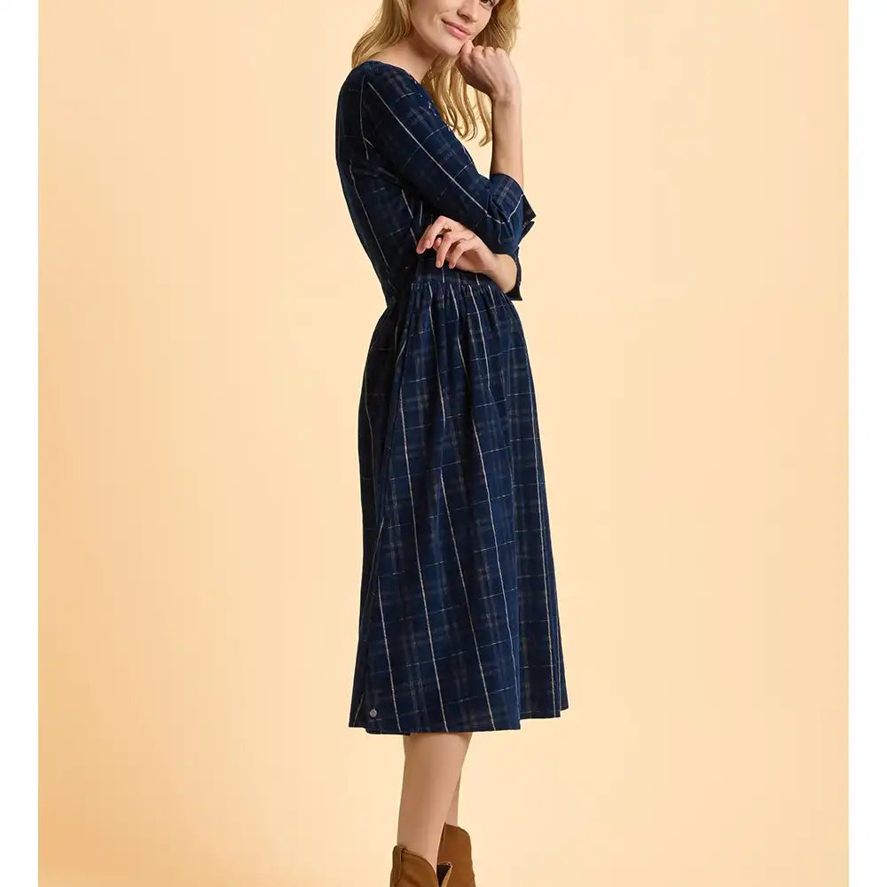 Woman wearing a blue plaid dress against a beige background