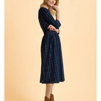 Woman wearing a blue plaid dress against a beige background