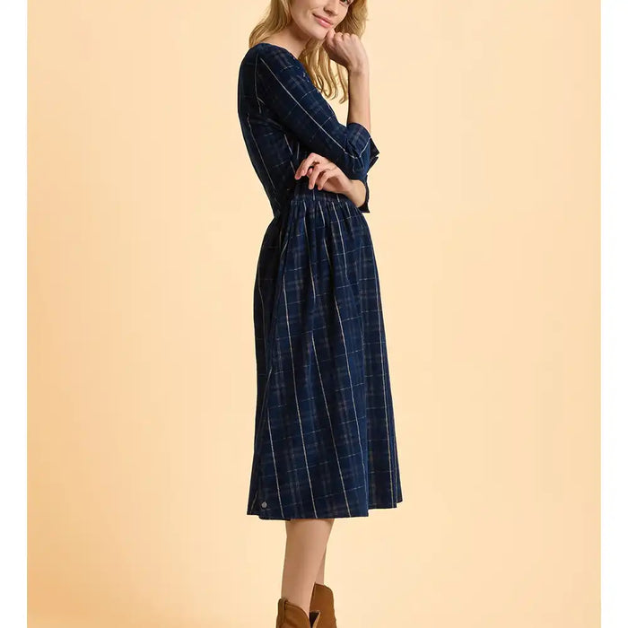 Woman wearing a blue plaid dress against a beige background