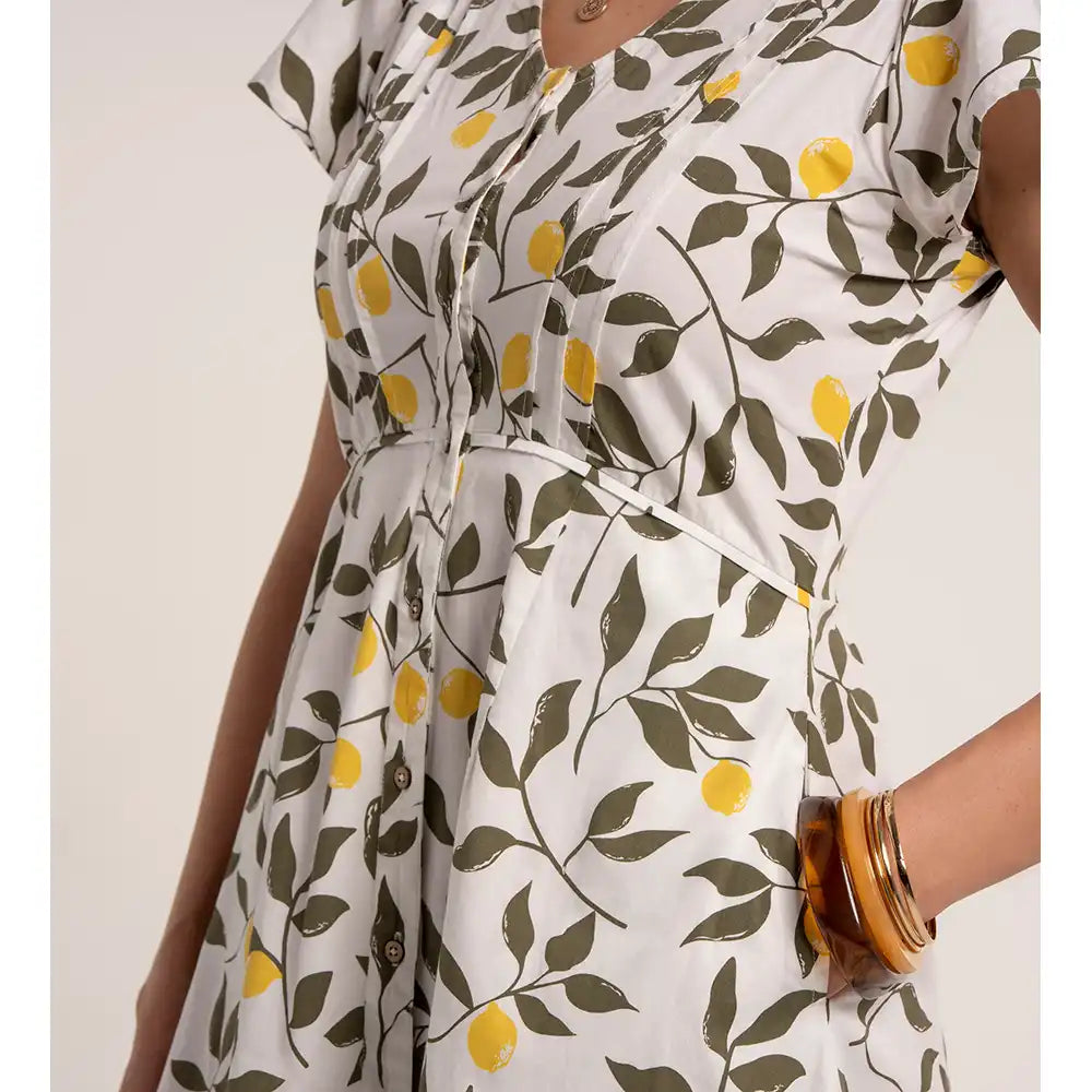 White dress with lemon and leaf pattern worn by a person on a white background