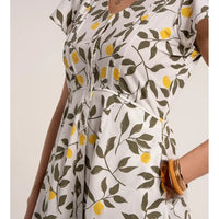 White dress with lemon and leaf pattern worn by a person on a white background