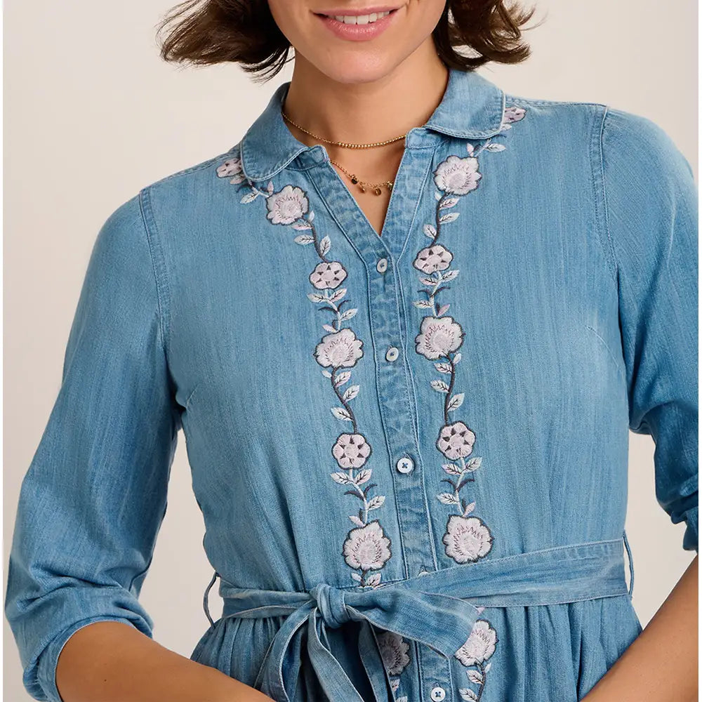 Blue denim dress with floral embroidery on a neutral background