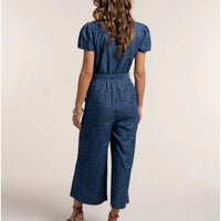 Woman wearing a blue patterned jumpsuit on a plain background