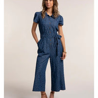 Woman wearing a blue patterned jumpsuit on a beige background