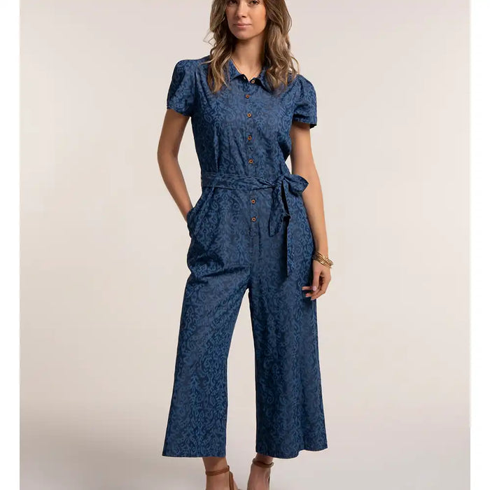 Woman wearing a blue patterned jumpsuit on a beige background