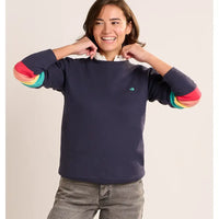 Person wearing a navy sweater with colorful sleeves on a beige background