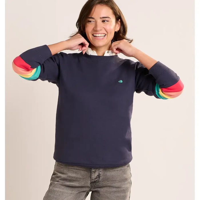 Person wearing a navy sweater with colorful sleeves on a beige background