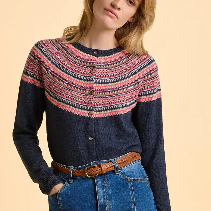Woman wearing a navy sweater with colorful pattern and blue jeans on a beige background