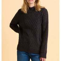 Person wearing a dark brown knitted sweater against a beige background