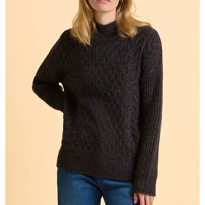 Person wearing a dark brown knitted sweater against a beige background