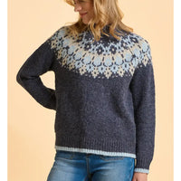 Person wearing a dark blue knitted sweater with a patterned yoke against a beige background