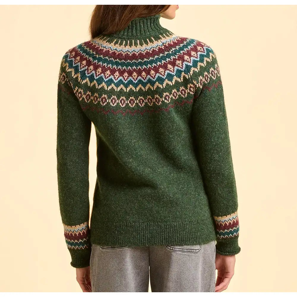 Green sweater with a colorful pattern on the back, worn by a person against a beige background