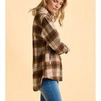 Woman wearing a plaid shirt and jeans on a beige background