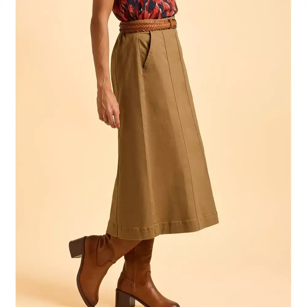 Person wearing a brown skirt and boots on a beige background