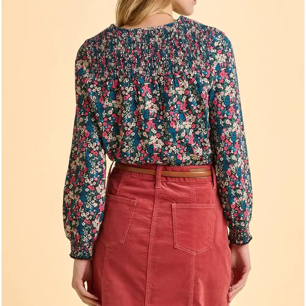 Person wearing a floral blouse and red pants on a beige background