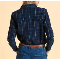 Person wearing a blue plaid shirt and jeans on a beige background