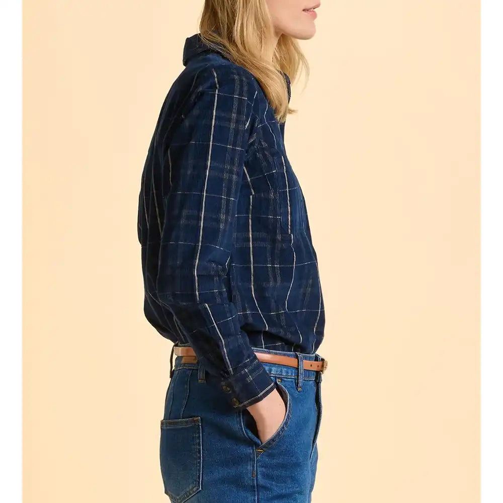 Person wearing a blue plaid shirt and jeans on a beige background