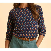 Person wearing a navy blue floral patterned shirt with rolled-up sleeves on a beige background