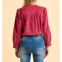 Person wearing a red blouse and blue jeans on a beige background