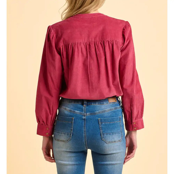 Person wearing a red blouse and blue jeans on a beige background