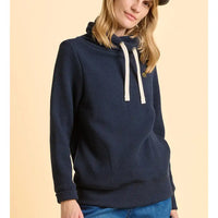 Person wearing a navy blue hoodie with a beige background