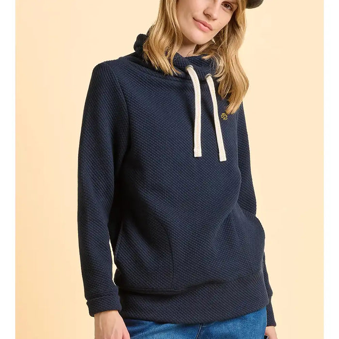 Person wearing a navy blue hoodie with a beige background