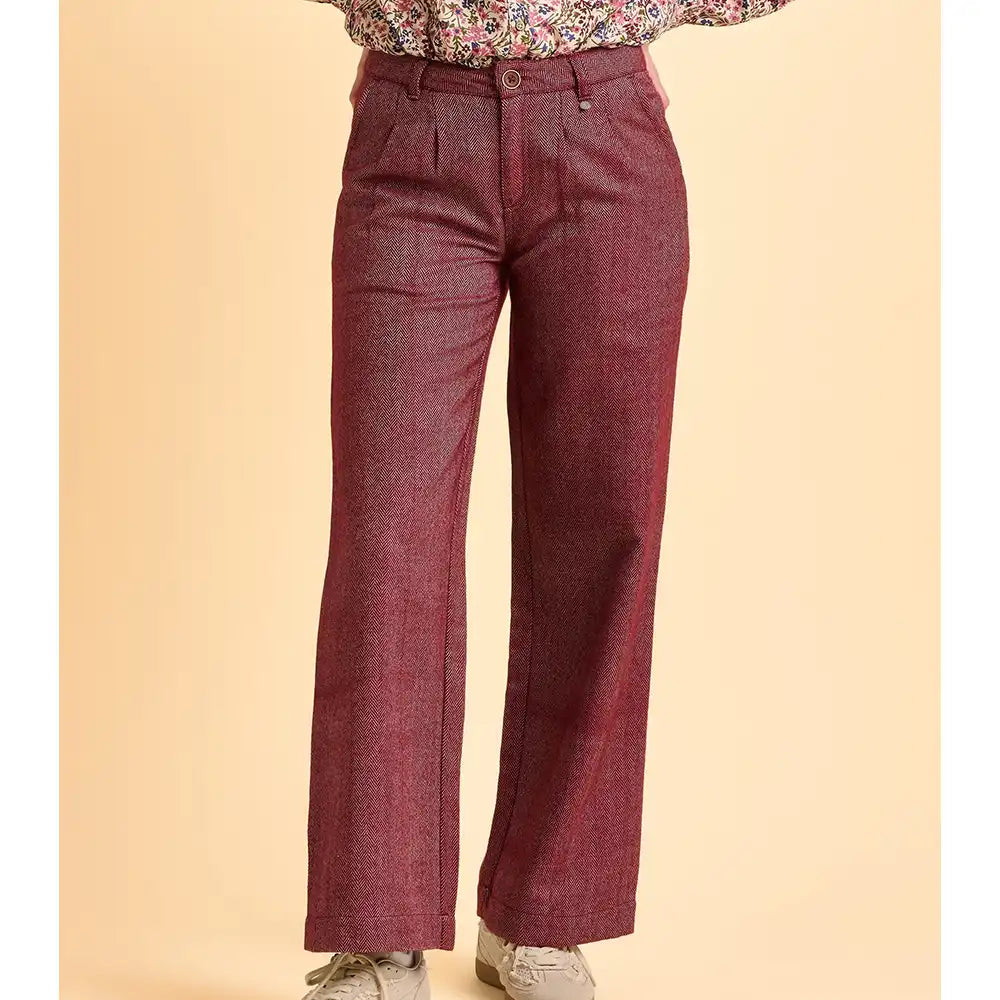 Maroon pants worn with a floral top on a beige background