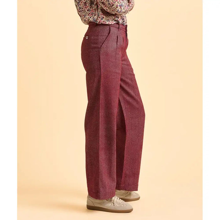 Maroon high-waisted pants worn by a person on a beige background