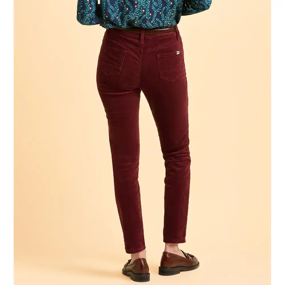 Maroon pants worn by a person on a beige background