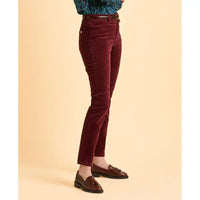 Maroon velvet pants worn by a person on a beige background