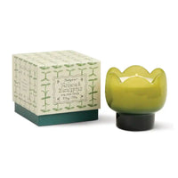 Green candle with decorative wick and matching box on a white background