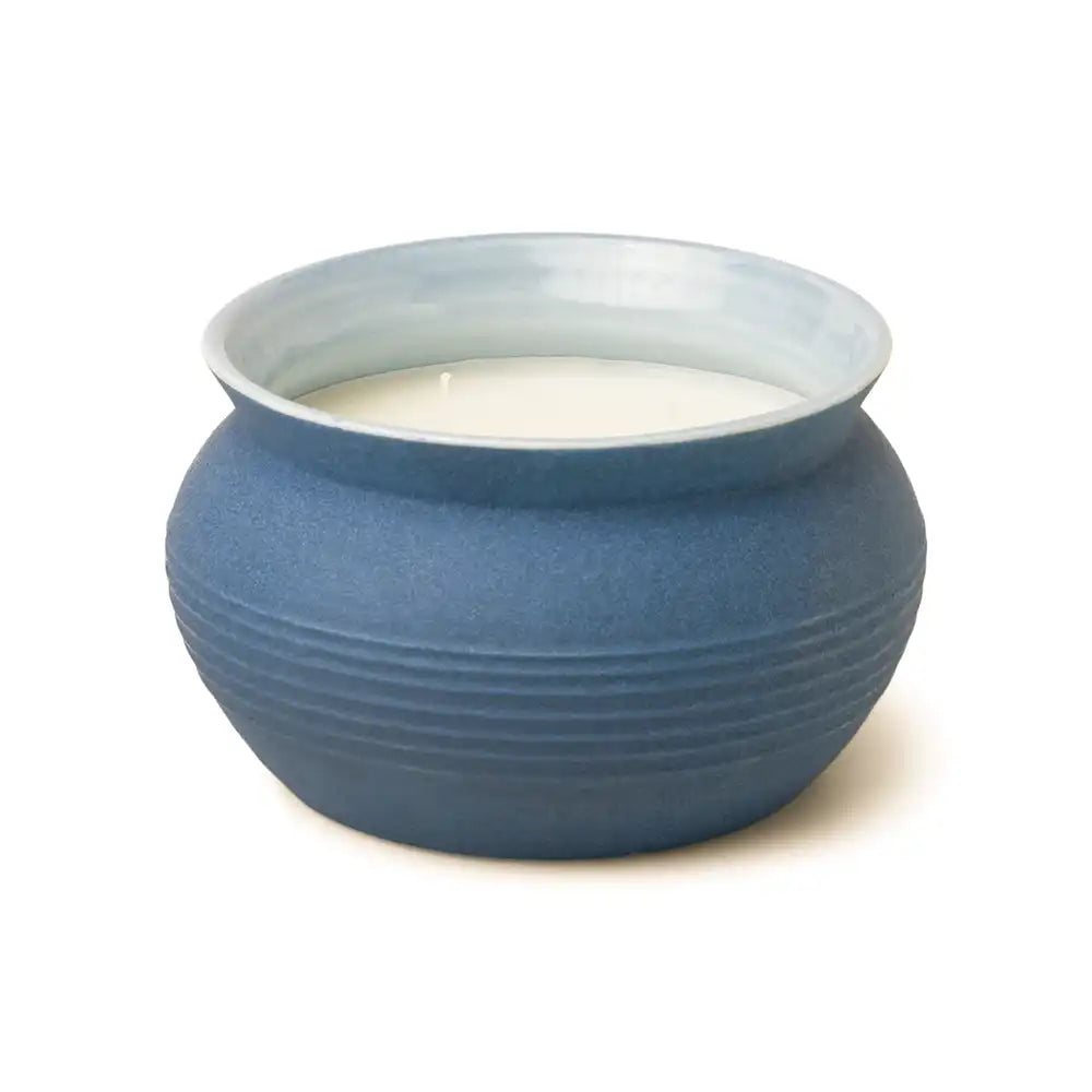 Blue ceramic bowl with a white candle inside on a white background