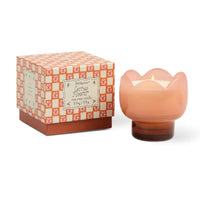 Orange glass tulip holder with candle. Orange floral decorative box next to it. 

