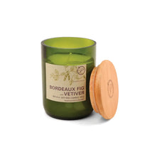 Green candle in a glass jar with a wooden lid on a white background