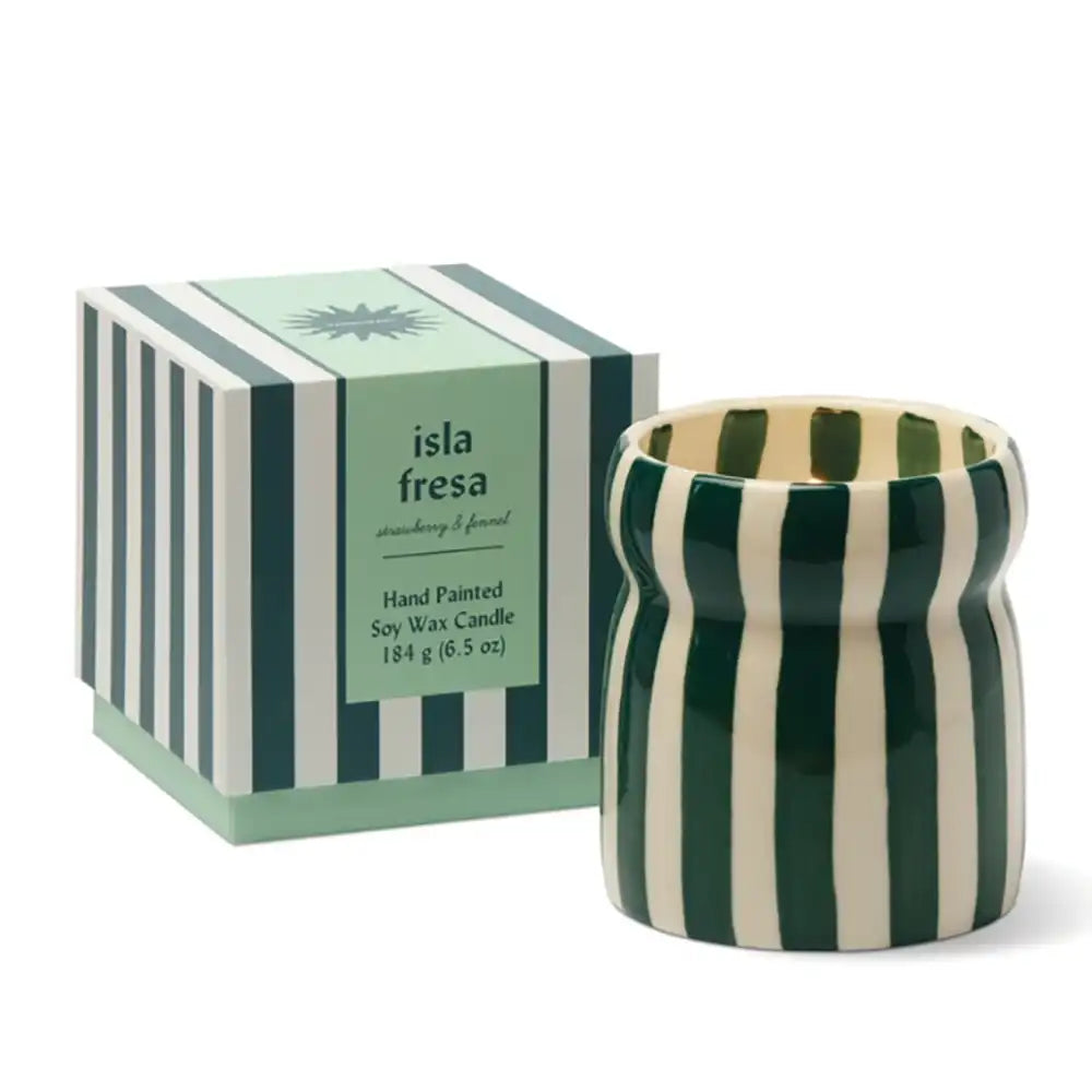 A hand-painted soy wax candle in a ribbed ceramic pot with dark green and cream vertical stripes, shown next to its matching striped packaging box labeled 'isla fresa'.