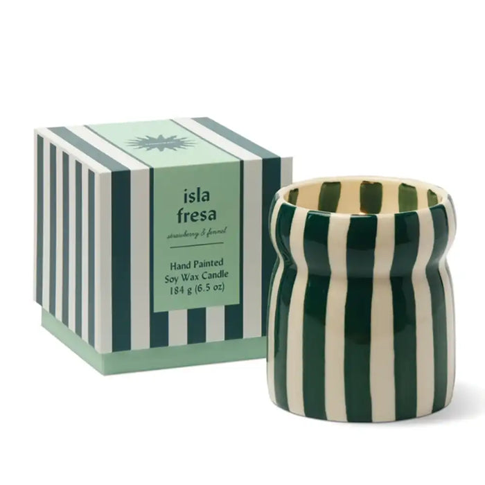 A hand-painted soy wax candle in a ribbed ceramic pot with dark green and cream vertical stripes, shown next to its matching striped packaging box labeled 'isla fresa'.